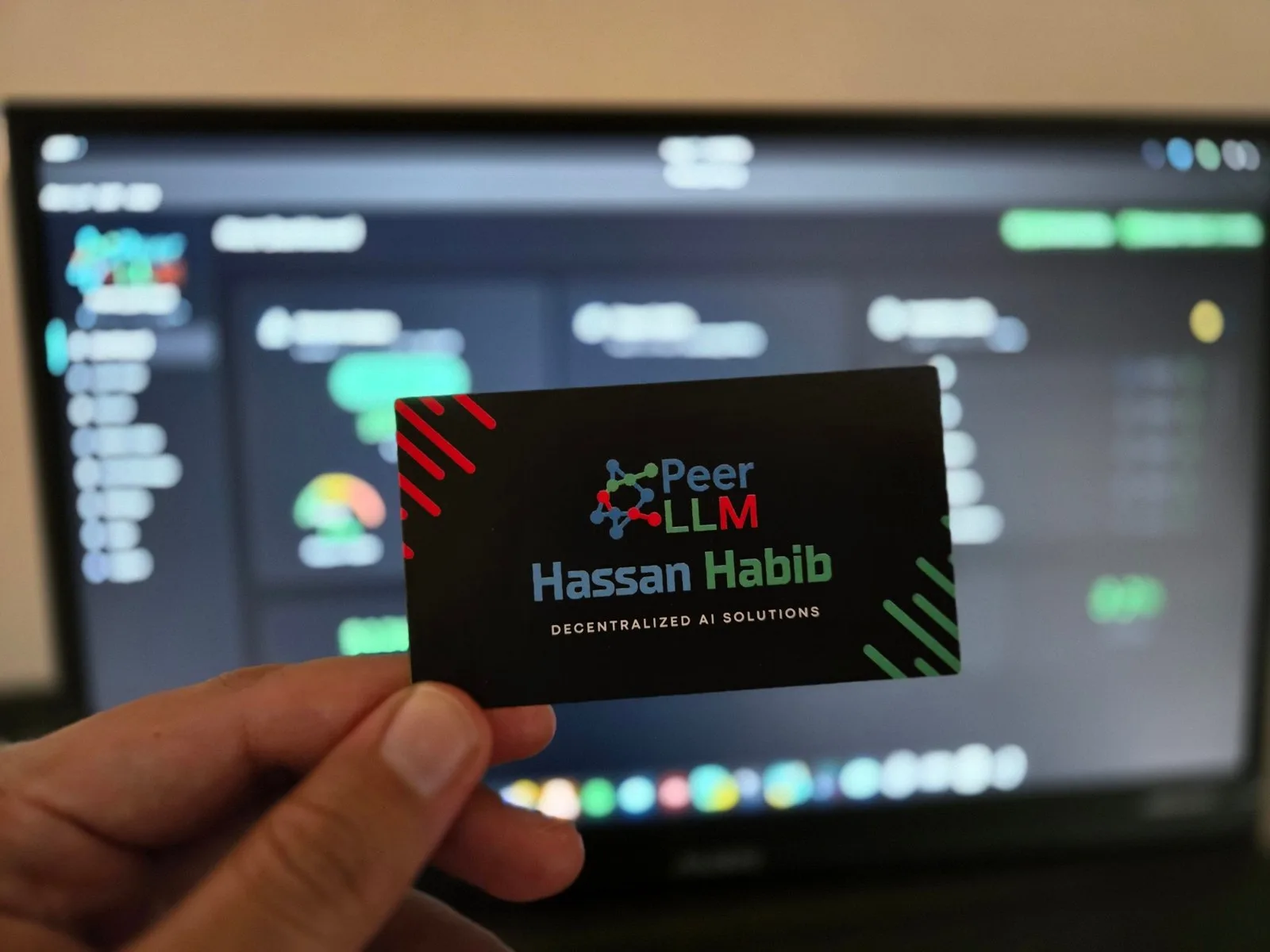 A PeerLLM card with Hassan's name on it, held up in front of a network dashboard
